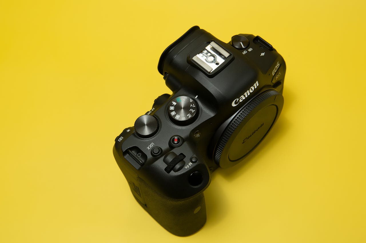 Close-up of a professional DSLR camera against a vibrant yellow background, showcasing detailed controls.